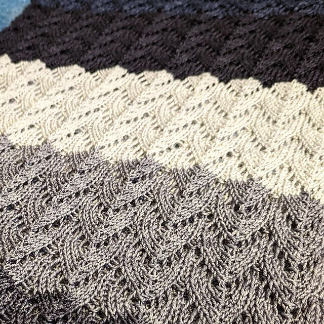Close up on Longma's Cowl, a repeating whale tail patterned worked in a grey gradient.